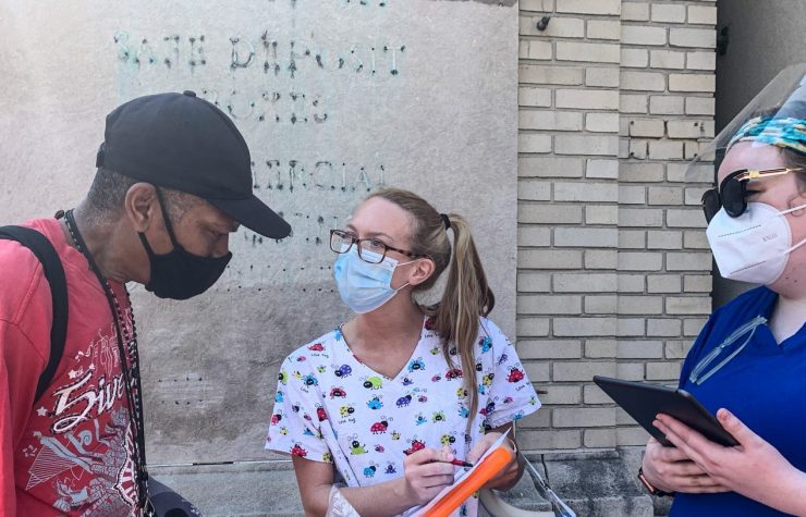 Maddie Boyes, RN (right), and Hayley Carper, RN (center), two students at the University of Maryland School of Nursing, help William Lipmann, a West Baltimore community member, get registered for a vaccine appointment. Lipmann also was able to make an appointment for his elderly mother. Photo by Jena Frick