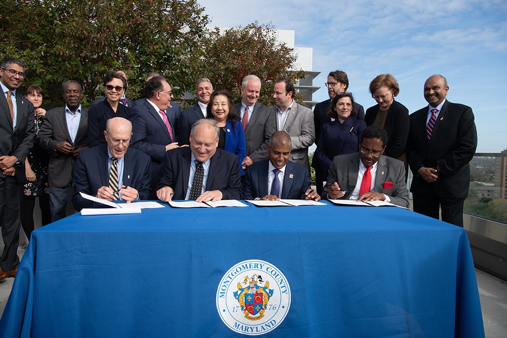 Bruce E. Jarrell, UMB president (left); Marc Elrich, Montgomery County executive; Darryll J. Pines, UMCP president; and Mohan Suntha, president and CEO of UMMS sign the memorandum of understanding to create the University of Maryland Institute for Health Computing. Photo by Matthew D’Agostino