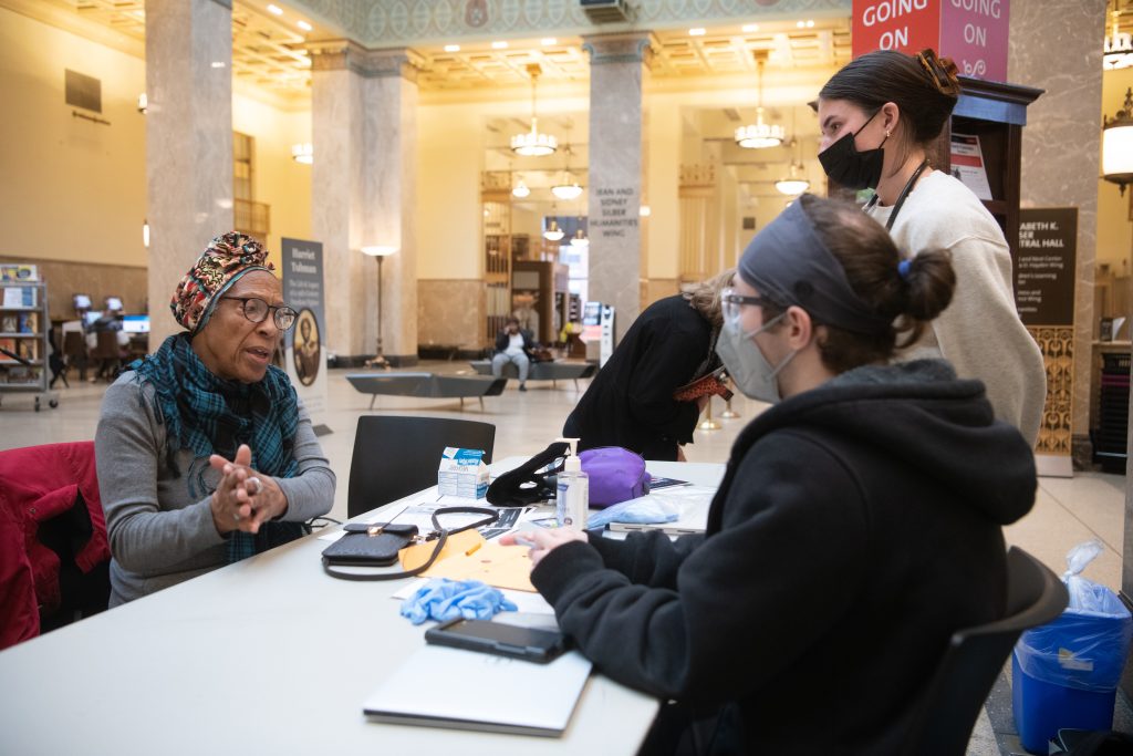 A Pratt Library patron talks to nursing students who are working at the library in a partnership to provide free services such as blood pressure checks and health screenings to the community. Photo by Matthew D’Agostino