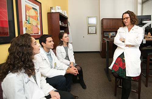 Donna Parker, MD, FACP (right), senior associate dean for medical education and chief academic officer for the Medical Education Program, addressing a few medical students in an office.