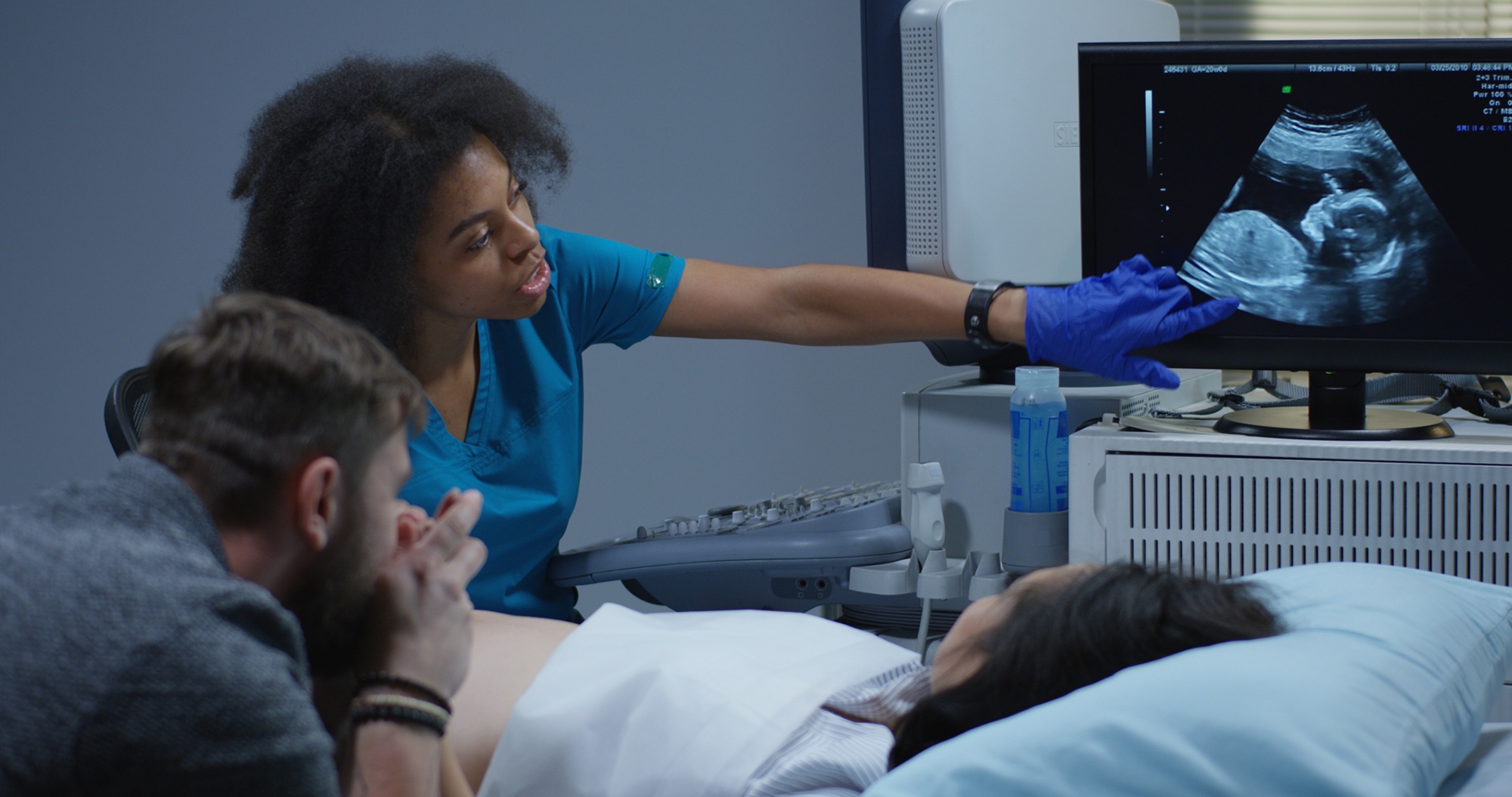 Medium shot of a young female doctor examining a pregnant woman with ultrasound